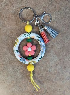 a keychain with a flower and tassels on it sitting on the ground