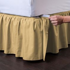 a person is holding the edge of a bed skirt