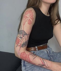 a woman sitting on a couch with tattoos on her arm