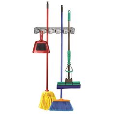 three brooms, two mop heads and one dustpan are hanging on the wall