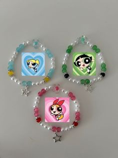 three bracelets with cartoon characters on them and beads around the edges, all decorated in different colors