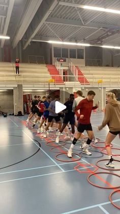 a group of people on a basketball court playing with hoop rings in an indoor gym