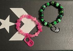 two bracelets with pink and green beads, one has a pair of scissors on it