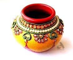 an orange decorated vase sitting on top of a white table