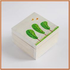 a wooden box with leaves painted on the front and sides, sitting on a white surface