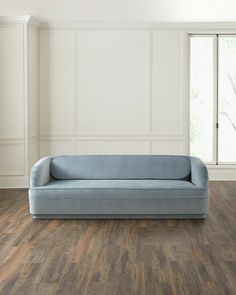 a blue couch sitting on top of a hard wood floor next to a white wall