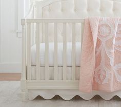 a white crib with a pink blanket on it