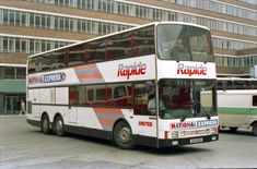 a double decker bus is parked in front of a building with another bus behind it