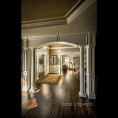 an archway leads to the living room and dining room in this house with hardwood floors