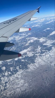 the wing of an airplane flying over snow covered mountains