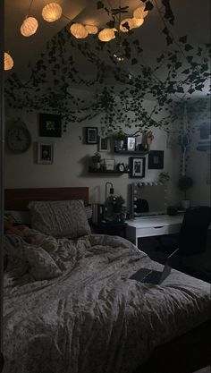 an unmade bed in a room with lights hanging from the ceiling and pictures on the wall