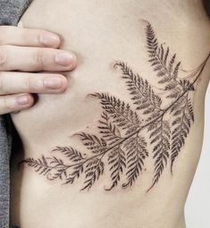 a woman's stomach with a tattoo design on the side of her belly and leaves