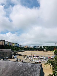 boats are parked on the beach in front of some buildings and trees, under a cloudy blue sky