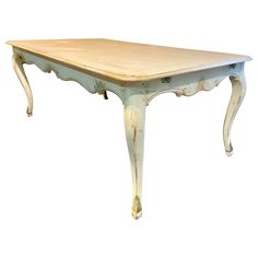 an old wooden table with white paint on the top and legs, against a white background