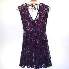 a dress hanging on a hanger in front of a white wall with a black and purple lace top