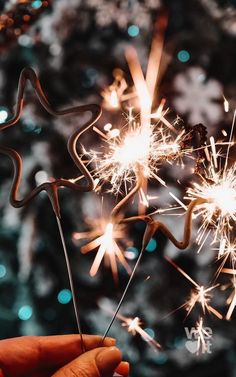 someone is holding sparklers in front of a christmas tree