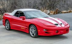 a red sports car parked in front of some rocks