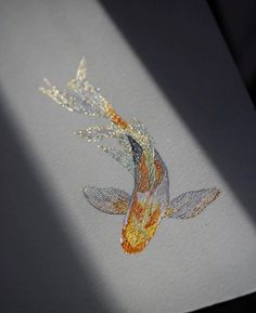 a drawing of a goldfish on white paper with orange and blue colors in the water