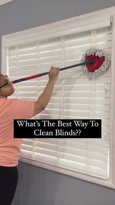 a woman is cleaning the window blinds with a mop and a red heart on it