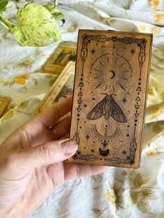 a person holding up a wooden box with a moth on it