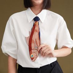 a woman wearing a white shirt and tie with fish on it's lapel