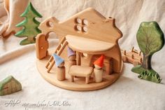 a wooden toy house with toys surrounding it