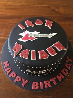 a birthday cake with the words iron maiden on it and an image of a guitar