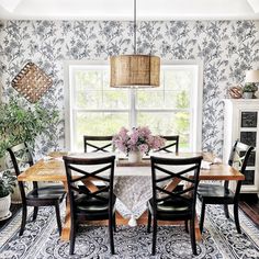 the dining room table is surrounded by black and white wallpaper with floral designs on it