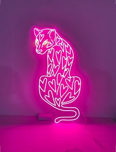 a pink neon sign with a cat on it's back lit up in the dark