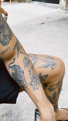 a man with tattoos on his legs sitting down