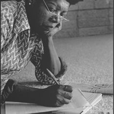 a woman is laying on the floor writing with a pen and paper in front of her