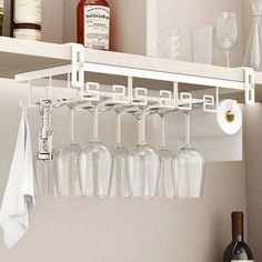 there is a wine glass rack in the kitchen with many glasses hanging from it's hooks