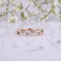 an image of a wedding ring with diamonds on it and flowers in the background,