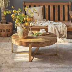 a coffee table with flowers on it in front of a wooden bench and couches