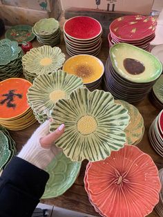 a table topped with lots of plates covered in different colored designs and shapes on top of each other