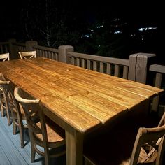 a wooden table and chairs on a deck at night