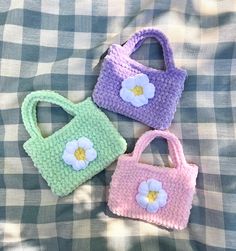 three crocheted purses sitting on top of a plaid cloth covered bedding