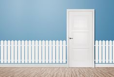 an empty room with a white door and wooden floor in front of a blue wall