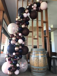 a bunch of balloons that are hanging from the side of a wooden barrel in front of a staircase