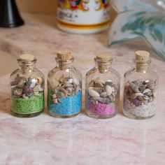 three glass bottles filled with sand and shells