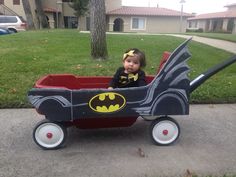 a baby in a batman wagon on the sidewalk