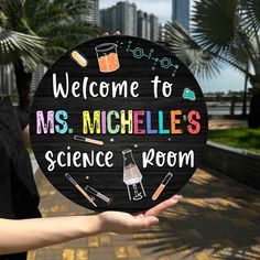 a person holding up a sign that says welcome to ms michelies science room