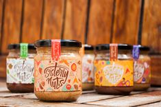 five jars of peanut butter sitting on top of a wooden table