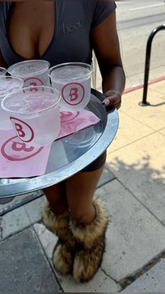 a woman holding a tray with cups on it