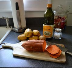 potatoes and carrots on a cutting board next to a bottle of olive oil