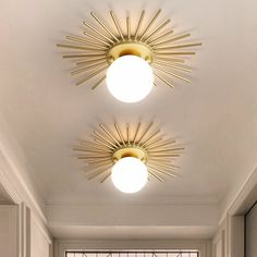 two sunburst lights are hanging from the ceiling in a room with white walls