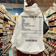 a person wearing a hoodie that says jesus paid it all in front of a grocery aisle