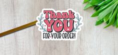 a thank you for your order sticker next to some green leaves on a table