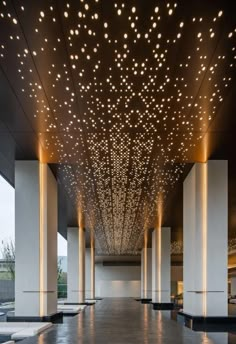 an indoor walkway with lights on the ceiling and columns in front of it at night