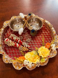 a decorative tray with two silver bowls on top of it and yellow flowers in the middle